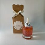 Frasco de vidro com óleo hidratante iluminador, com tom bronze e embalagem elegante.